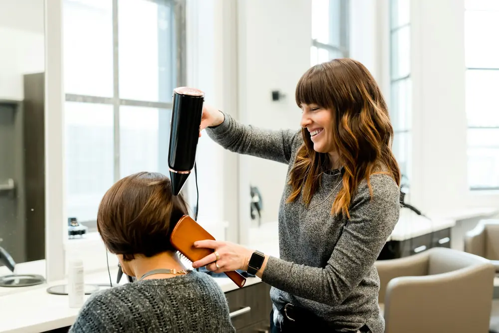 Une coiffeuse coiffe une cliente dans son salon