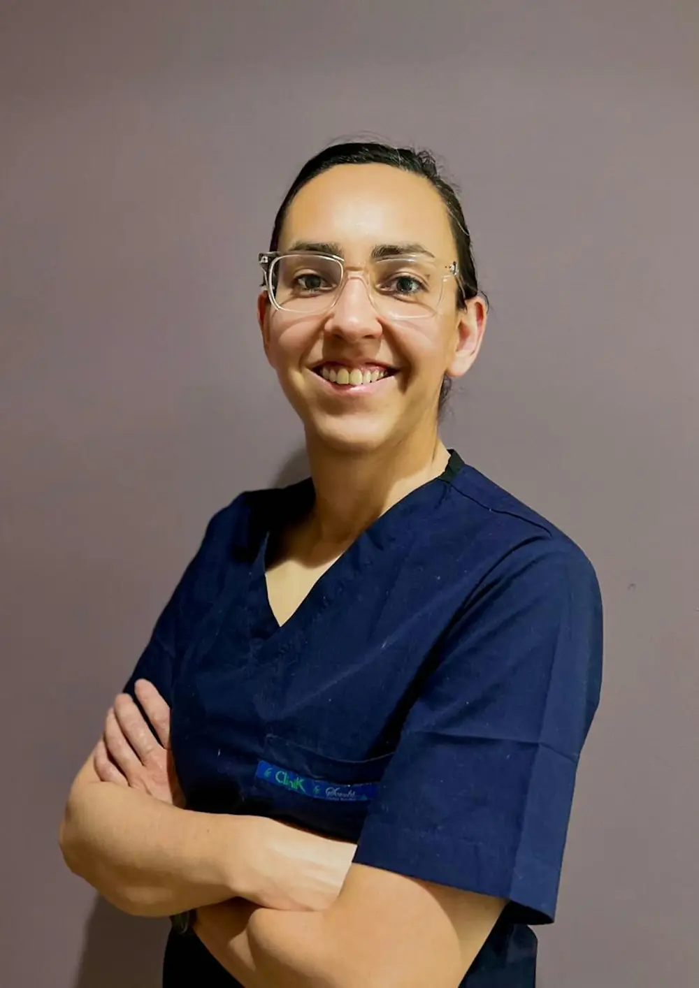 Une praticienne souriante en tenue de soin